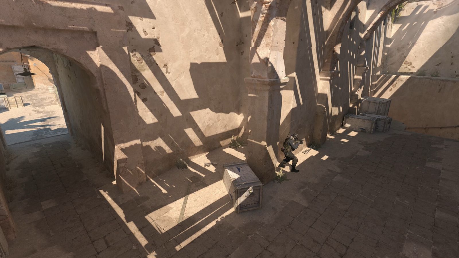 CS2 players moving through the long shadows of Dust II mid