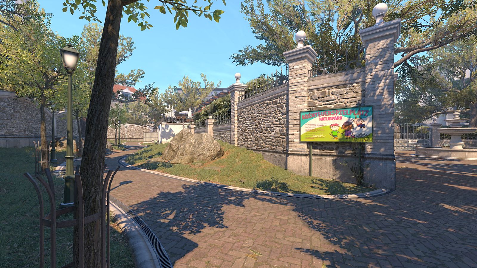 Counter-Strike 2 view down long A on Overpass, a sunlit path between trees, grass and a stone wall towards the park